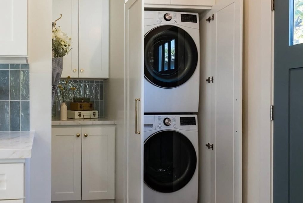 Modern apartment laundry nook hidden behind white folding doors
